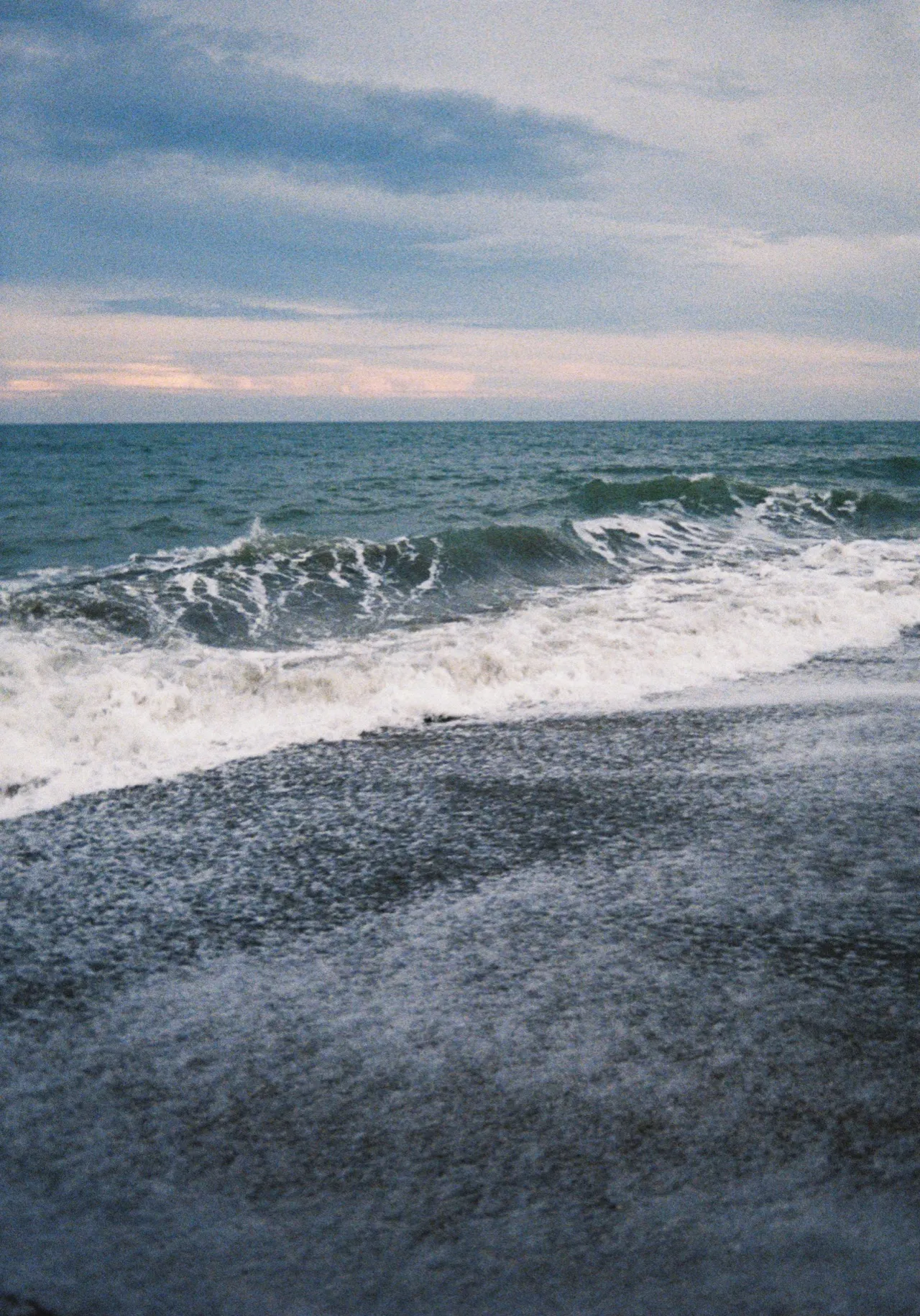 夕暮れの浜に崩れる波
